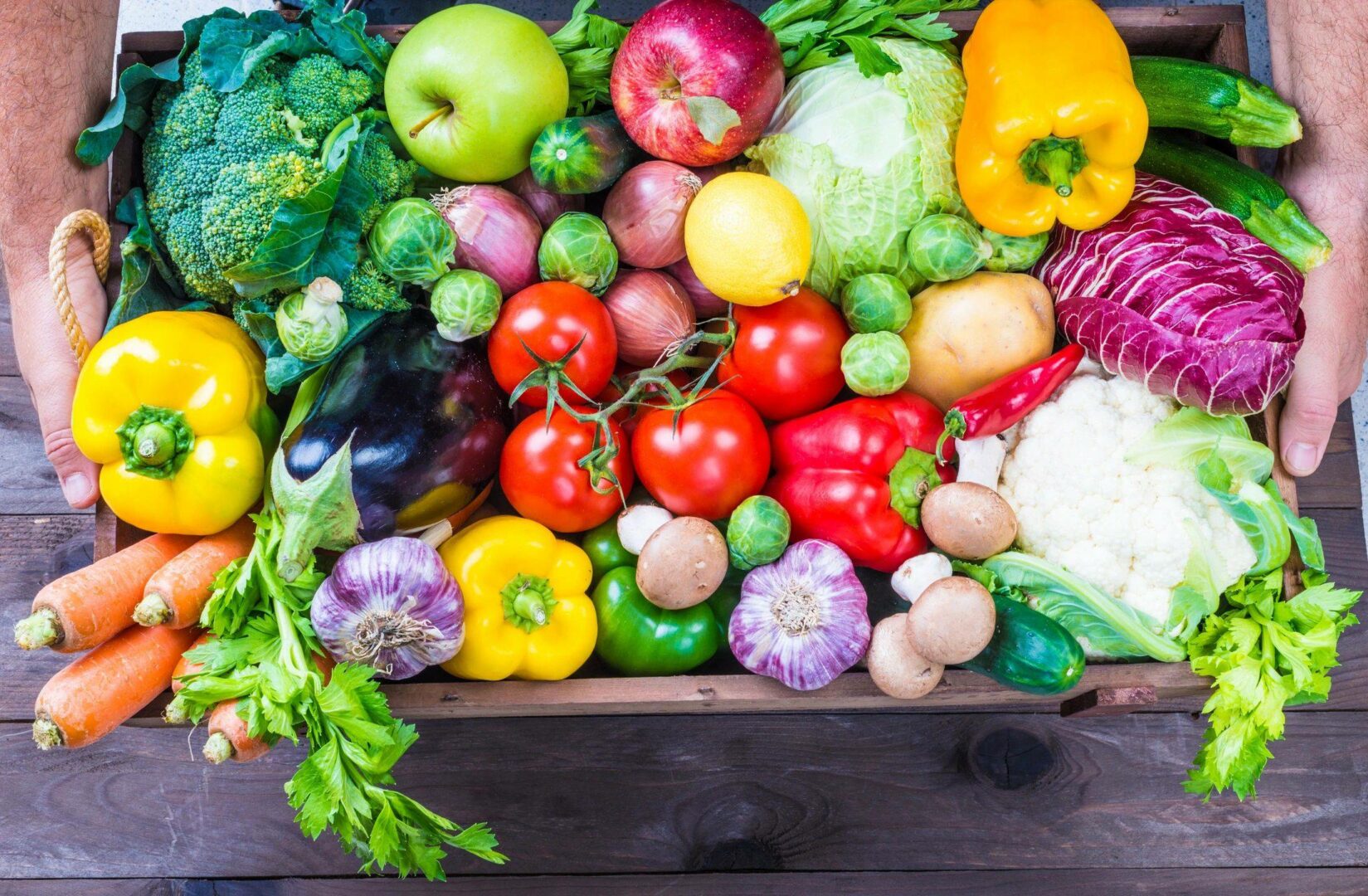 A wooden box filled with lots of different fruits and vegetables.