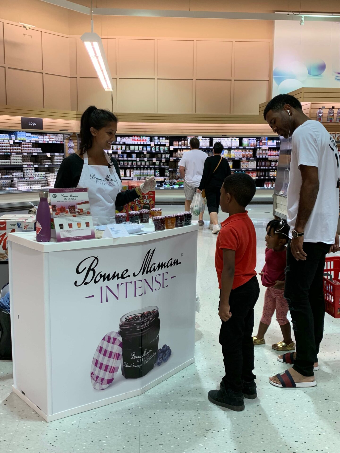 A woman and two men standing in front of a counter.